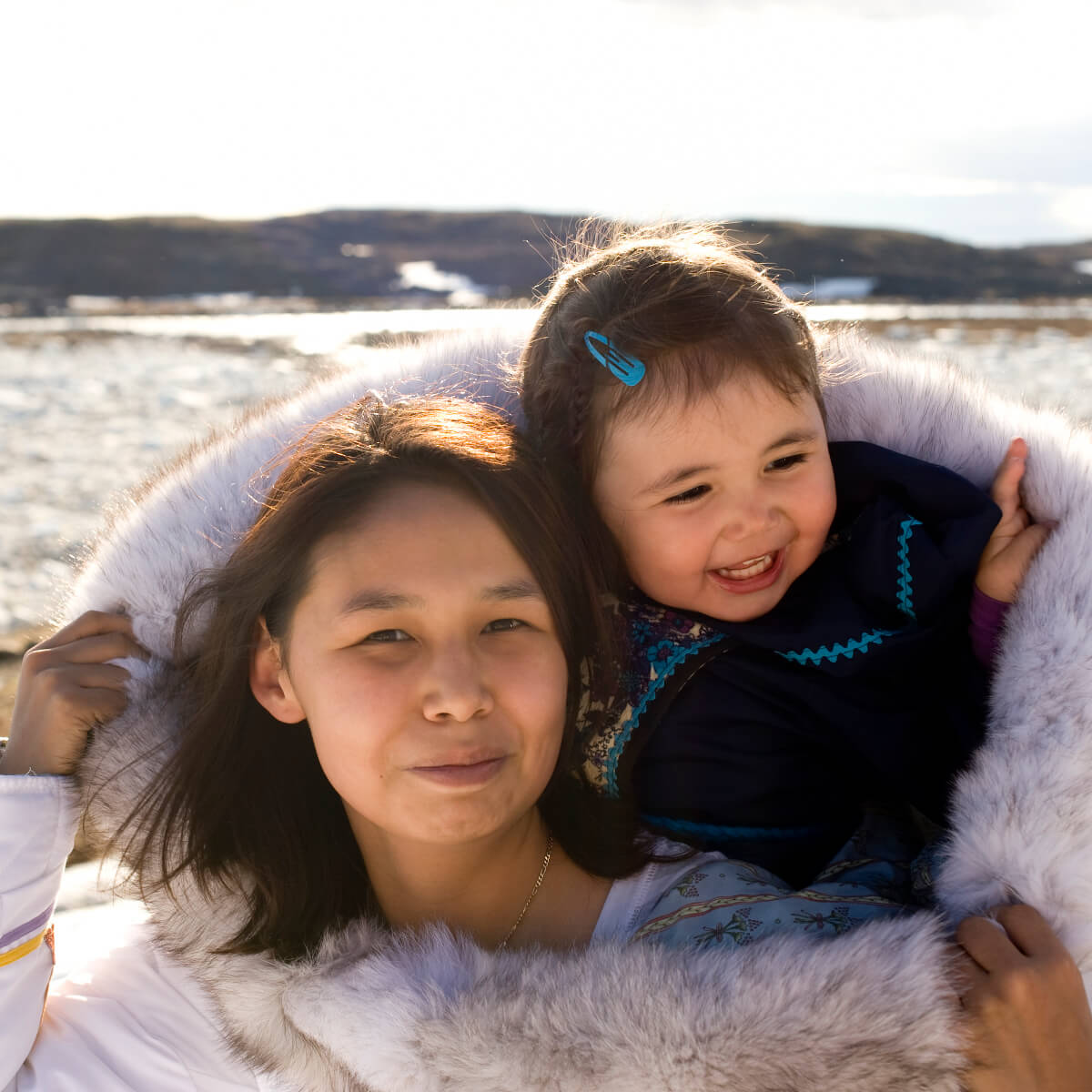 An Inuit mother carries her daugher on her back in her amouti which is a traditional coat. Nunavut. Canada